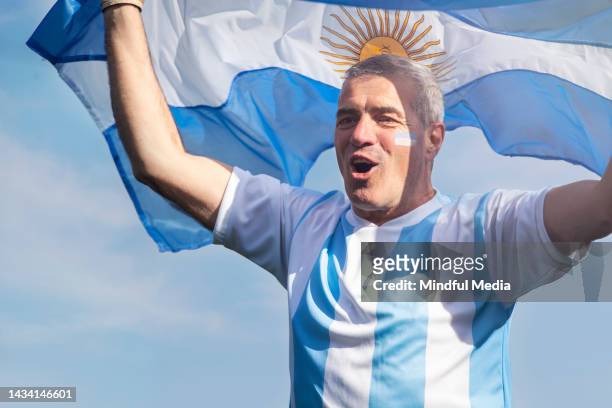 happy argentinian football fan waving a flag while celebrating outside stadium - argentinian flag stock pictures, royalty-free photos & images