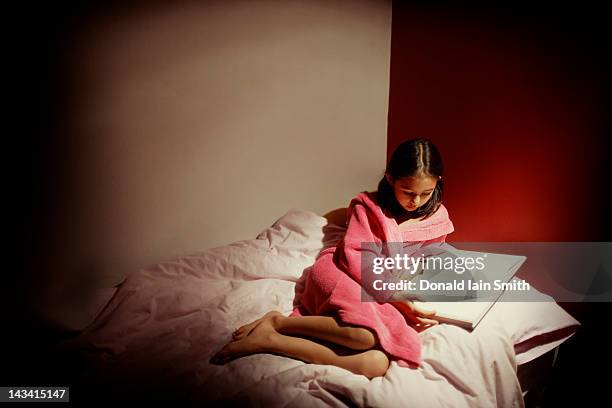 young girl reading by lamp light - alleen één meisje stockfoto's en -beelden