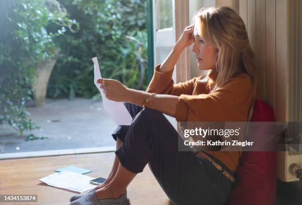 woman reading a letter, looking overwhelmed - crisis response stock pictures, royalty-free photos & images