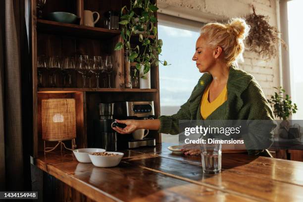 ältere kaukasische frau, die zu hause espresso macht. - espressomaschine stock-fotos und bilder