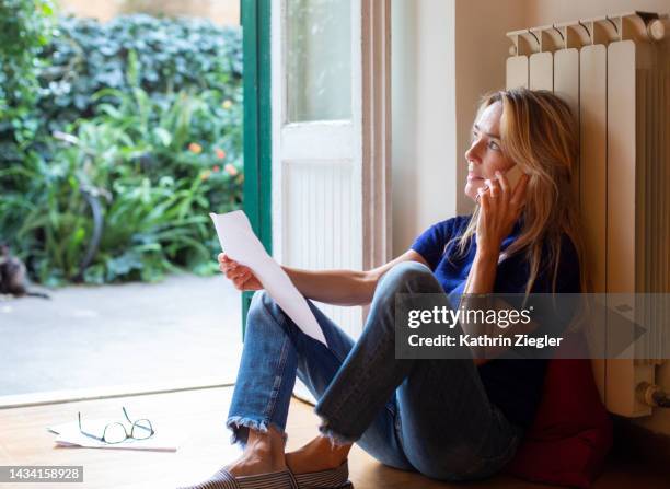 woman holding a letter, talking on mobile phone - unhappy woman blonde glasses stock pictures, royalty-free photos & images