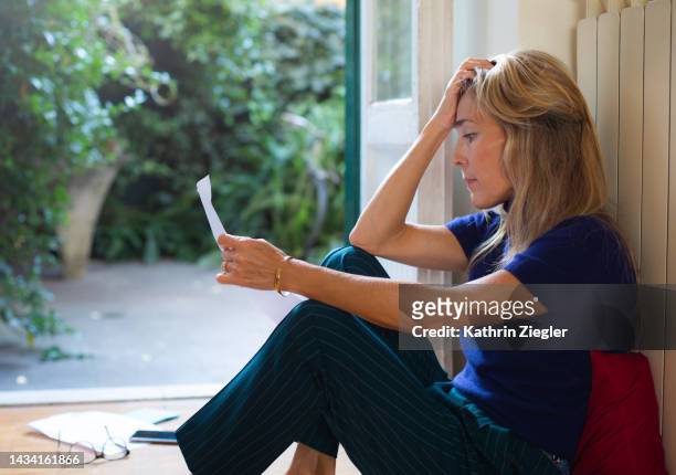 woman reading a letter, looking overwhelmed - sad woman stockfoto's en -beelden