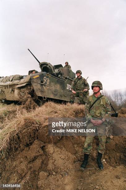Sergeant Steve Norris from Pismo Beach, California, and Lt. Jeff Schall from Pittsburg stand guard next to their Bradley fighting vehicle as work on...