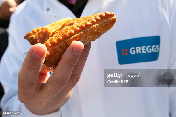 An employee of Greggs bakery holds a pasty as he joins demonstrators outside Downing Street in London on April 26, 2012 to protest and deliver a...