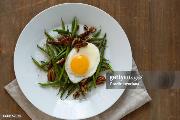 healthy breakfast with fried egg served in plate with sauteed green beans and pecan - legume family stock pictures, royalty-free photos & images