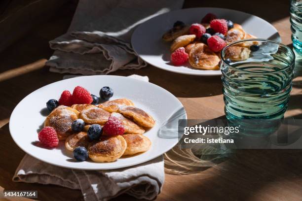 breakfast, dutch mini pancakes poffertjes served in white plate with fresh raspberries - dutch pancakes stockfoto's en -beelden