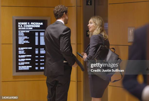 Former Theranos CEO Elizabeth Holmes talks with her partner Billy Evans as they arrive at federal court on October 17, 2022 in San Jose, California....