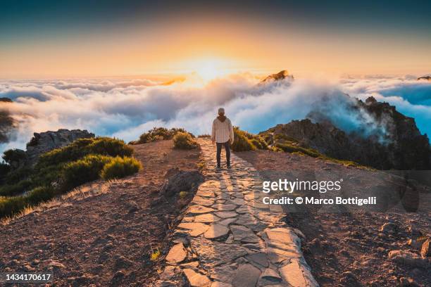 man admiring sunset from pathway on mountain ridge - pico do arieiro fotografías e imágenes de stock