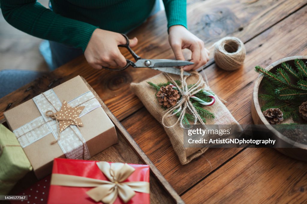 Mujer preparando regalo de navidad en estilo rústico con materieals cero desperdicio.