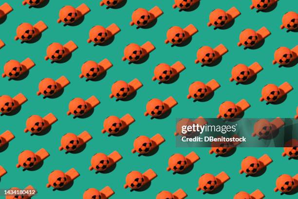 pattern of orange plastic whistles in the shape of a soccer ball on a green background. concept of world cup, competition, referee, rules, punishment, penalty and penalty. - spelregels stockfoto's en -beelden
