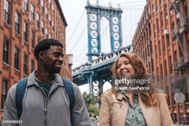 couple marchant dans les rues à la découverte de new york - manhattan bridge photos et images de collection