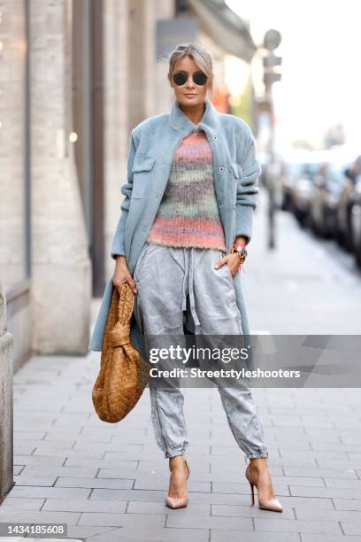 Influencer Gitta Banko wearing a multicolored striped knitted pullover by Roberto Collina, a long grey faux fur coat by Betta Corradi, a camel...