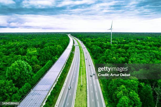 aerial view of a green highway and railway tunnel covered with solar panels in belgium. - meerdere baans snelweg stockfoto's en -beelden