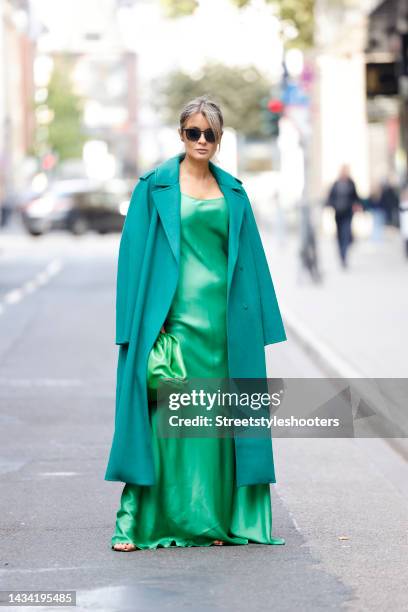 Influencer Gitta Banko wearing a green maxi dress by Victoria Beckham, a green long coat by Arma, a green bag by Simone Bruns and gold high heel...