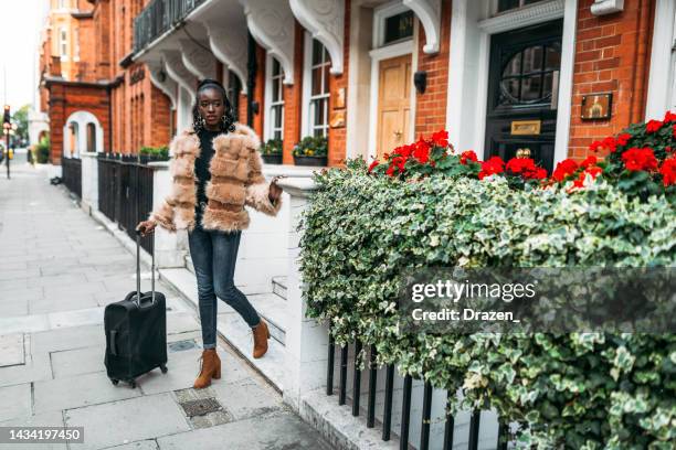 african tourist with suitcase leaving the hotel - hospitality lounge at the longines global champions tour of london stockfoto's en -beelden