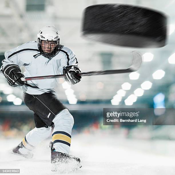 puck shot by ice hockey player - hockey player stock-fotos und bilder