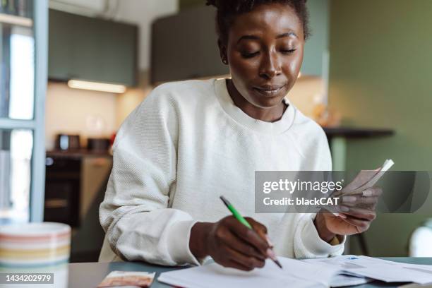 afroamerikanische frau, die geld hält und ausgaben zählt - women euro stock-fotos und bilder