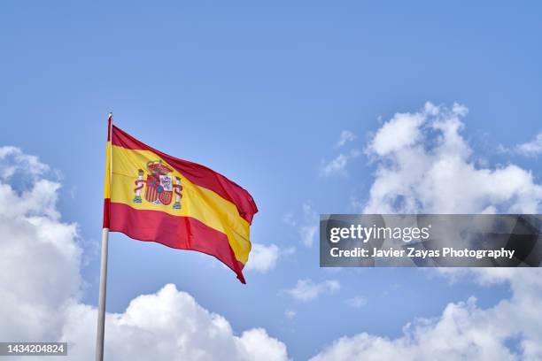 spanish flag waving against blue sky - spanische flagge stock-fotos und bilder