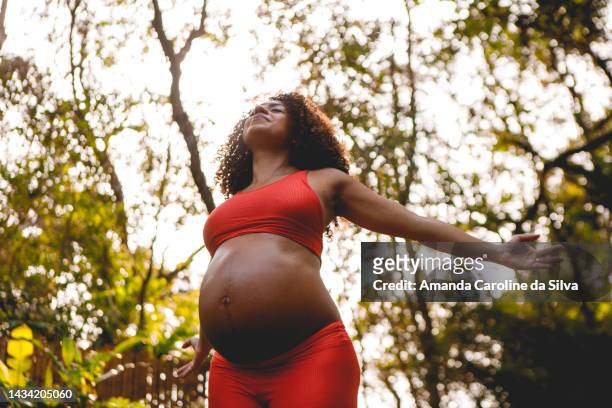 femme noire enceinte faisant du yoga à l’extérieur - femme enceinte jardin photos et images de collection