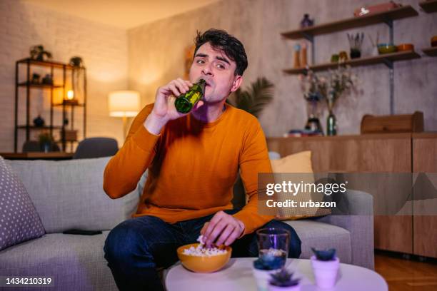 young man watching a sports game at home - man cave stock pictures, royalty-free photos & images