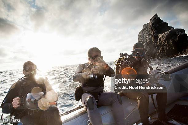 scuba divers dive off of an inflatable boat - buceo con equipo fotografías e imágenes de stock