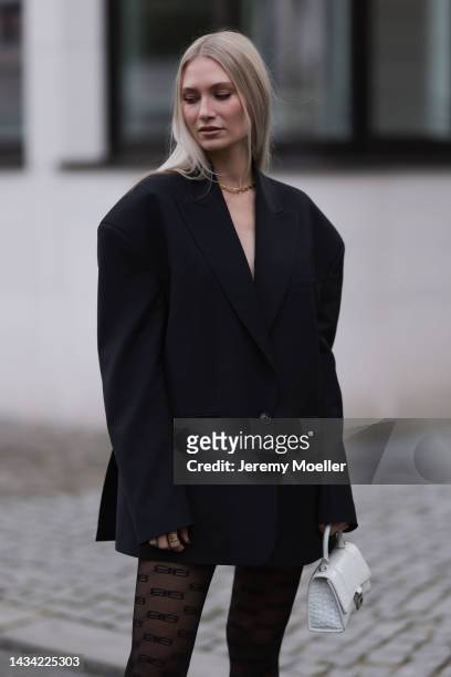 Carolin Niemczyk wearing Balenciaga hourglass white leather bag, Balenciaga logo tights, black oversized blazer and gold chain on October 15, 2022 in...