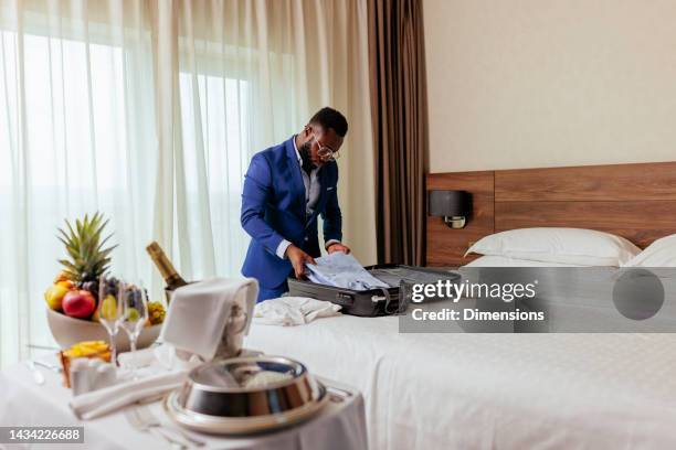 man unpacking in luxurious hotel room. - hotel bedroom stock pictures, royalty-free photos & images