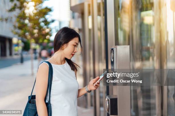 young businesswoman entering office building with smart phone - center for secure computing stock pictures, royalty-free photos & images