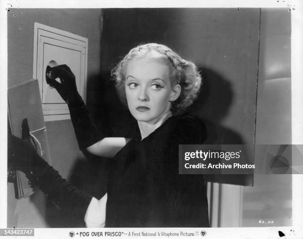 Bette Davis opening up safe in a scene from the film 'Fog Over Frisco', 1934.
