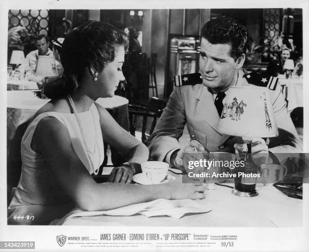 Andra Martin and James Garner sitting at table together in a scene from the film 'Up Periscope', 1959.