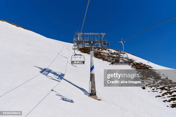 view of a cable car in a ski resort, showing the towers, the wiring and the shadows cast on the snow by the reflection of the sun. - chute ski stock-fotos und bilder