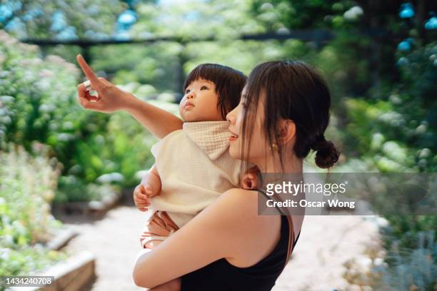 young asian woman living a sustainable lifestyle with her toddler daughter - baby pointing stockfoto's en -beelden