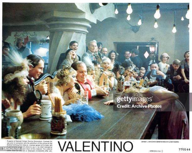 Crowd laughs as woman passes out at the bar in a scene from the film 'Valentino', 1977.
