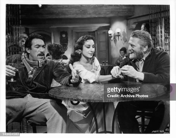 Anthony Quinn, Pamela Brown, and Kirk Douglas sitting at bar table together in a scene from the film 'Lust For Life', 1956.