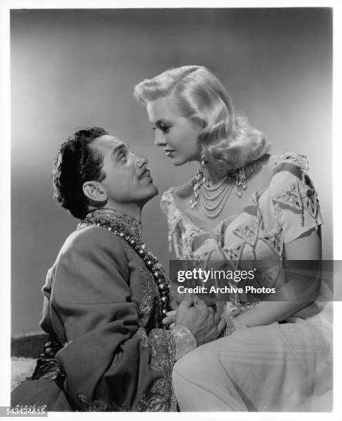 John Conte looking up into the eyes of Marilyn Maxwell in a scene from the film 'Lost In A Harem', 1944.