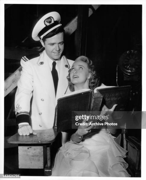 Thomas E Breen looking at book over the shoulder of Jane Powell in a scene from the film 'Luxury Liner', 1948.