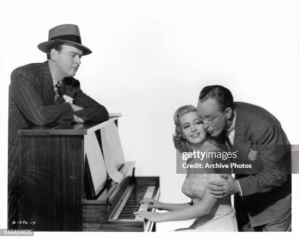 William Gargan watching over Marilyn Maxwell and Kay Kyser at the piano in a scene from the film 'Swing Fever', 1943.