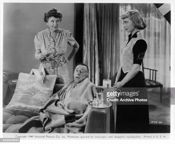 Percy Kilbride wrapped in blanket with Marjorie Main and Meg Randall standing beside him in a scene from the film 'Ma and Pa Kettle', 1949.