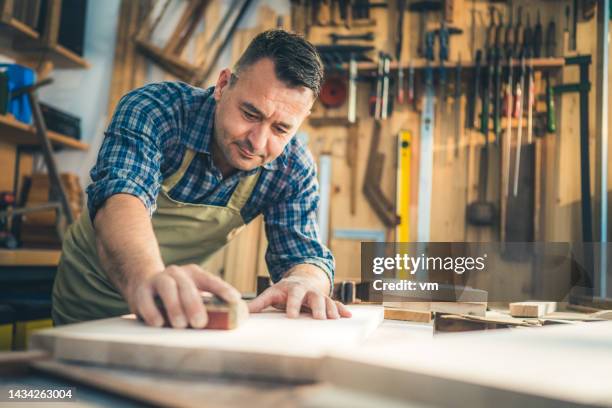 experienced carpenter adjusting surface of wooden plank - sand paper stock pictures, royalty-free photos & images