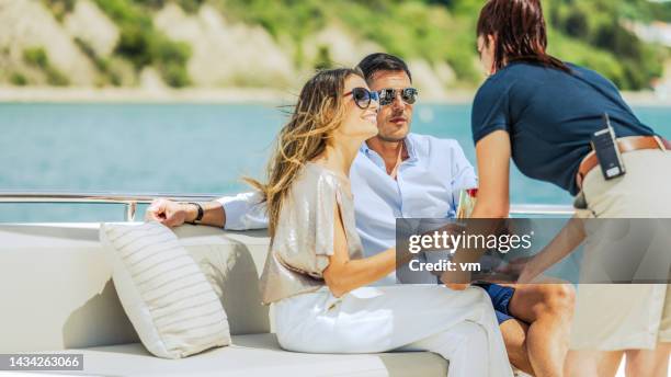 smiling woman and her partner getting glass of champagne - yacht stock pictures, royalty-free photos & images