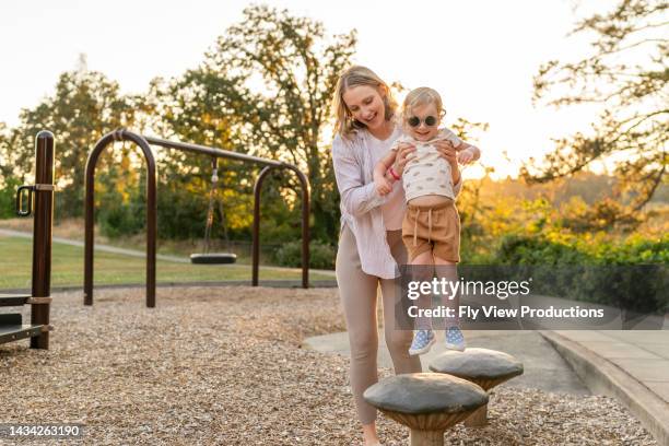 mutter und kleinkindtochter spielen im park - kinderspielplatz stock-fotos und bilder