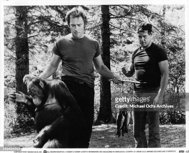 Manis the orangutan is walking away as Clint Eastwood holds fish on hooks and Geoffrey Lewis stands in the background in a scene from the film 'Any...