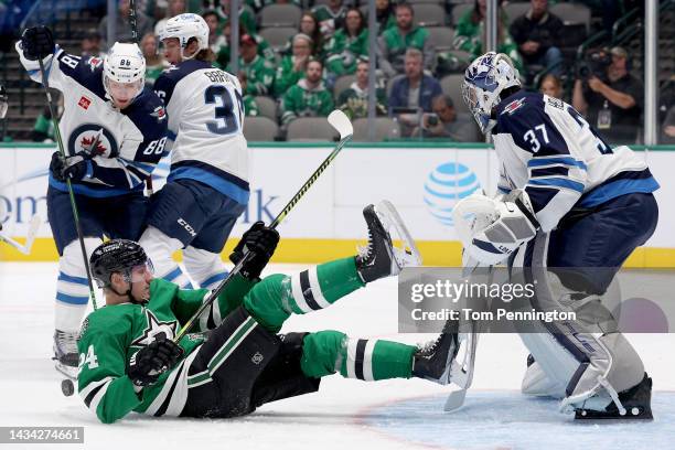 Roope Hintz of the Dallas Stars battles for the puck against Nate Schmidt of the Winnipeg Jets and Connor Hellebuyck of the Winnipeg Jets in the...