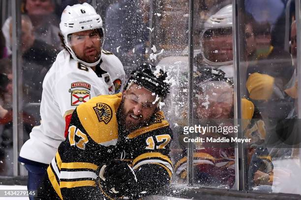 Colin White of the Florida Panthers checks Nick Foligno of the Boston Bruins into the boards during the first period at TD Garden on October 17, 2022...