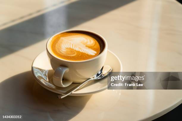 feshly brewed  latte coffee on a white table - coffee cup stock-fotos und bilder