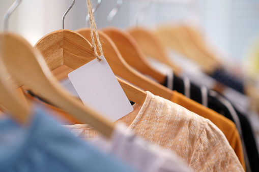 Blank paper labels hang on the clothes rails in the store