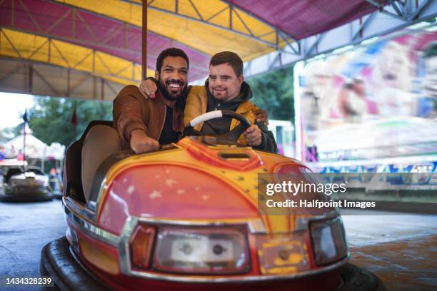 happy friends enjoying together traditional fair, riding bumper cars. - autoscooter stock-fotos und bilder