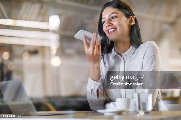 happy businesswoman recoding a message on her cell phone in the office. - ditafone imagens e fotografias de stock