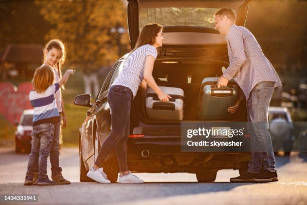 happy parents talking while loading luggage into car trunk. - boot stock pictures, royalty-free photos & images