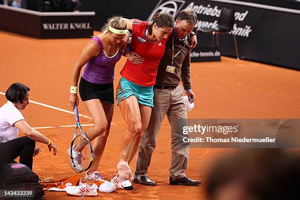 An injured Andrea Petkovic of Germany is taken off the court with the help of opponent Victoria Azarenka of Belarus during day four of the WTA...